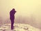 Abstract. Hiker in warm jacket enjoy view over snowy clouds. Winter mountain peak