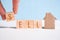 Abstract house made of cardboard hand holds with wooden cubes with the word sell. Home sale concept