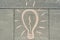 Abstract image drawing of light bulb written on grey sidewalk