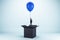 Abstract image of young european businessman flying on blue balloon out of black paper box on light background. Success, business