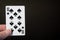 Abstract: man hand holding playing card ten spades on a black background with copyspace