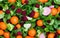 Abstract pattern of mandarins and berries in green leaves on a gray background