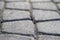 Abstract pattern of squared old-fashioned simple rough gray lit by sun concrete street cobblestone pavement. Construction, decorat