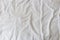 Abstract pattern of a white crumpled bed sheet in a hotel room. The manufacturing of bedsheet uses cotton, linen, silk