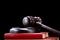 Abstract photo with wooden gavel and red book with codes on black background as symbol of of rule of law with judge`s gavel