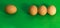 Abstract picture at Easter, three eggs lying close to each other and a single sad egg further away, on grass-green background