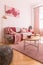 Abstract pink and burgundy painting on the empty wall of trendy native colors interior with stylish settee