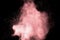 Abstract pink powder explosion on black background. Freeze motion of light pink dust splashing