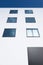 Abstract rectangular forms of windows in white wall reflect blue sky and clouds