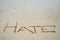 Abstract sign of word hate written on a sand beach background