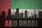 Abstract silhouette of the city with text Abu Dhabi at the vintage united arab emirates flag