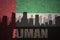 abstract silhouette of the city with text Ajman at the vintage united arab emirates flag