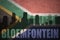 Abstract silhouette of the city with text Bloemfontein at the vintage south africa flag