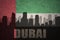 Abstract silhouette of the city with text Dubai at the vintage united arab emirates flag