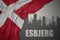 Abstract silhouette of the city with text Esbjerg near waving national flag of denmark on a gray background