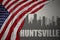 Abstract silhouette of the city with text Huntsville near waving colorful national flag of united states of america on a gray