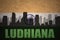Abstract silhouette of the city with text Ludhiana at the vintage indian flag