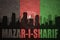 Abstract silhouette of the city with text Mazar-i-Sharif at the vintage afghanistan flag
