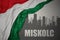 Abstract silhouette of the city with text Miskolc near waving national flag of hungary on a gray background