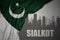 Abstract silhouette of the city with text Sialkot near waving national flag of pakistan on a gray background.3D illustration