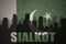 Abstract silhouette of the city with text Sialkot at the vintage pakistan flag