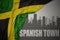 Abstract silhouette of the city with text Spanish Town near waving national flag of jamaica on a gray background. 3D illustration