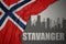 Abstract silhouette of the city with text Stavanger near waving national flag of norway on a gray background