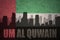 Abstract silhouette of the city with text Um Al Quwain at the vintage united arab emirates flag