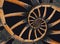 Abstract spiral wooden wagon cannon wheel with black metal brackets, rivets. Wheel wooden rim spokes background. Horse vehicle whe