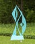 Abstract teal colored steel sculpture on a lawn in Dallas, Texas.