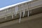 Abstract texture of icicles hanging down from a modern rain gutter in early spring