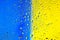 Abstract texture. Water drops on glass with blue and yellow background