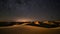 Abstract time lapse night sky with shooting stars over desert dune landscape. Milky way glowing lights background.