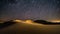 Abstract time lapse night sky with shooting stars over desert dune landscape. Milky way glowing lights background.