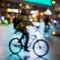 Abstract unrecognizable man silhouette, riding bikes, night city, illumination bokeh, motion blur. Healthy lifestyle