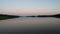 Abstract view of the closeup dandelion beside the lake during sunset through the horizon.