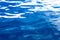 Abstract water background. Calm ocean water surface in intensive blue with curled white reflections