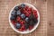 abundance of berries in a white bowl/ abundance of berries in a white bowl on a wooden background. Top view