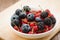 abundance of berries in a white bowl / abundance of berries in a white bowl on a wooden surface. Selective focus