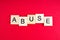 Abuse- word composed fromwooden blocks letters on red background, copy space for ad text.