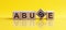 Abuse- word composed fromwooden blocks letters on yellow background, copy space for ad text