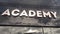 Academy sign on a modern glass skyscraper. Public education, learning, high school and university concept