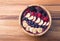 Acai berry smoothie in a wooden bowl topped with bananas, blueberries, raspberries and blackberries