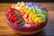 Acai bowl with strawberry, banana, blueberries, kiwi, mango and granola on wooden table. Nourishing breakfast full of vitamins,