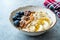 Acai Bowl with Yogurt, Blackberry, Banana Slices, Walnut, Honey, Jam, Oat, Almond, Sesame Seeds and Granola in Porcelain Bowl
