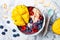 Acai breakfast superfoods smoothie bowl with mango, blueberry, cherry, coconut flakes. Overhead, top view