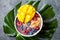 Acai breakfast superfoods smoothie bowl with mango, blueberry, cherry, coconut flakes. Overhead, top view