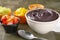 Acai on a white bowl with strawberry, mango and grape on colorful bowls over a stone background