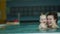 Accelerated video. Young mother teaches her year-old baby to dive in the pool. The child is delighted. The development