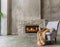Accent chair with fur throw against concrete wall with fireplace. Loft home interior design
